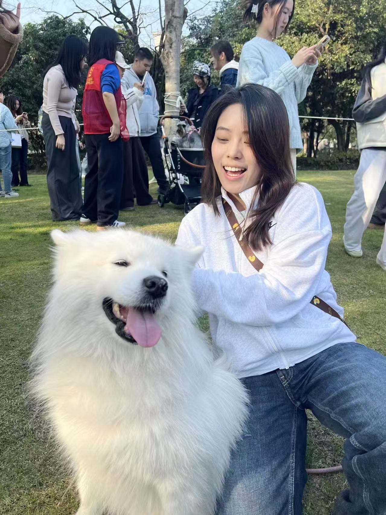 Gloria smiling with a white dog in the sun